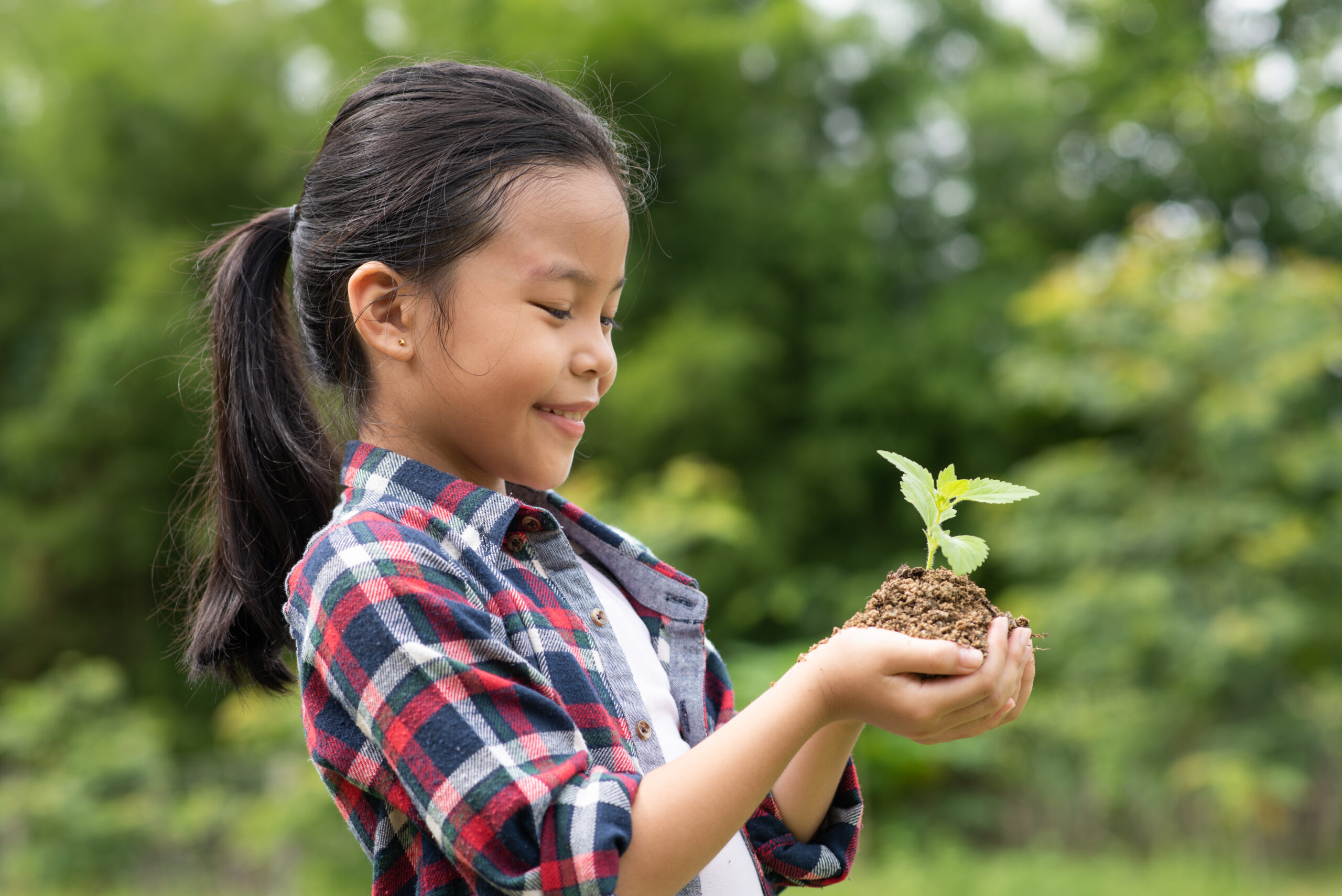 Asian girl standing at open space, close the eyes and hold the tree planted with smile, happy, love, care, share to reduce global warming for improve society, community and environment in the future